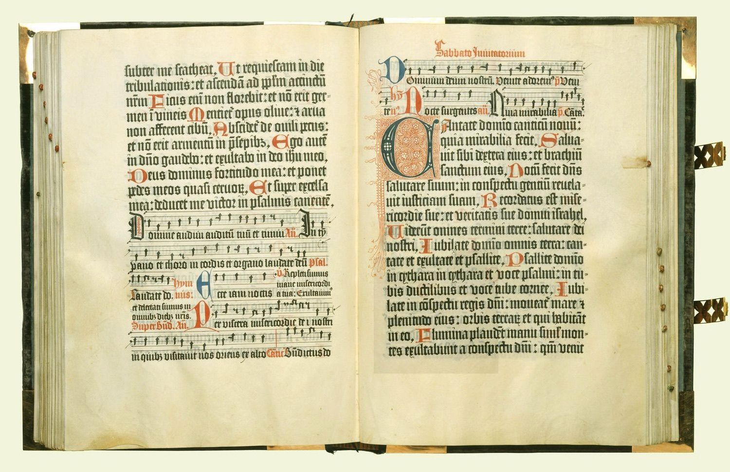 Uppslag ur Mainzpsaltaren från 1457. Tät svart text i en spalt per sida, med noter på notlinjer. Överst på högersidan står en rubrik i rött, och nedanför den en stor dekorerad initial i rött och blått som markerar att ett nytt avsnitt börjar. Mindre initialer i rött återkommer genom texten.